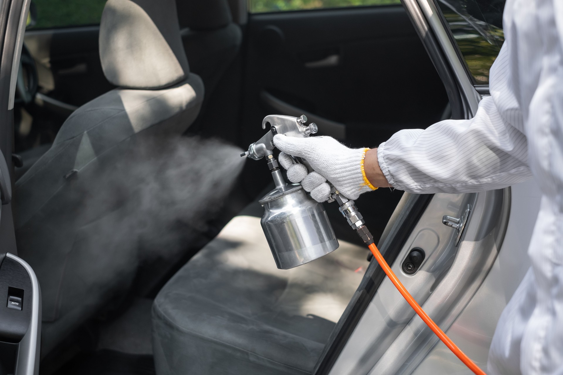 Nahaufnahme der Hand des Fachreinigers trägt persönliche Schutzausrüstung PSA mit chemischen Alkoholspray Reinigung im Auto zu desinfizieren und dekontaminieren Coronavirus covid-19
