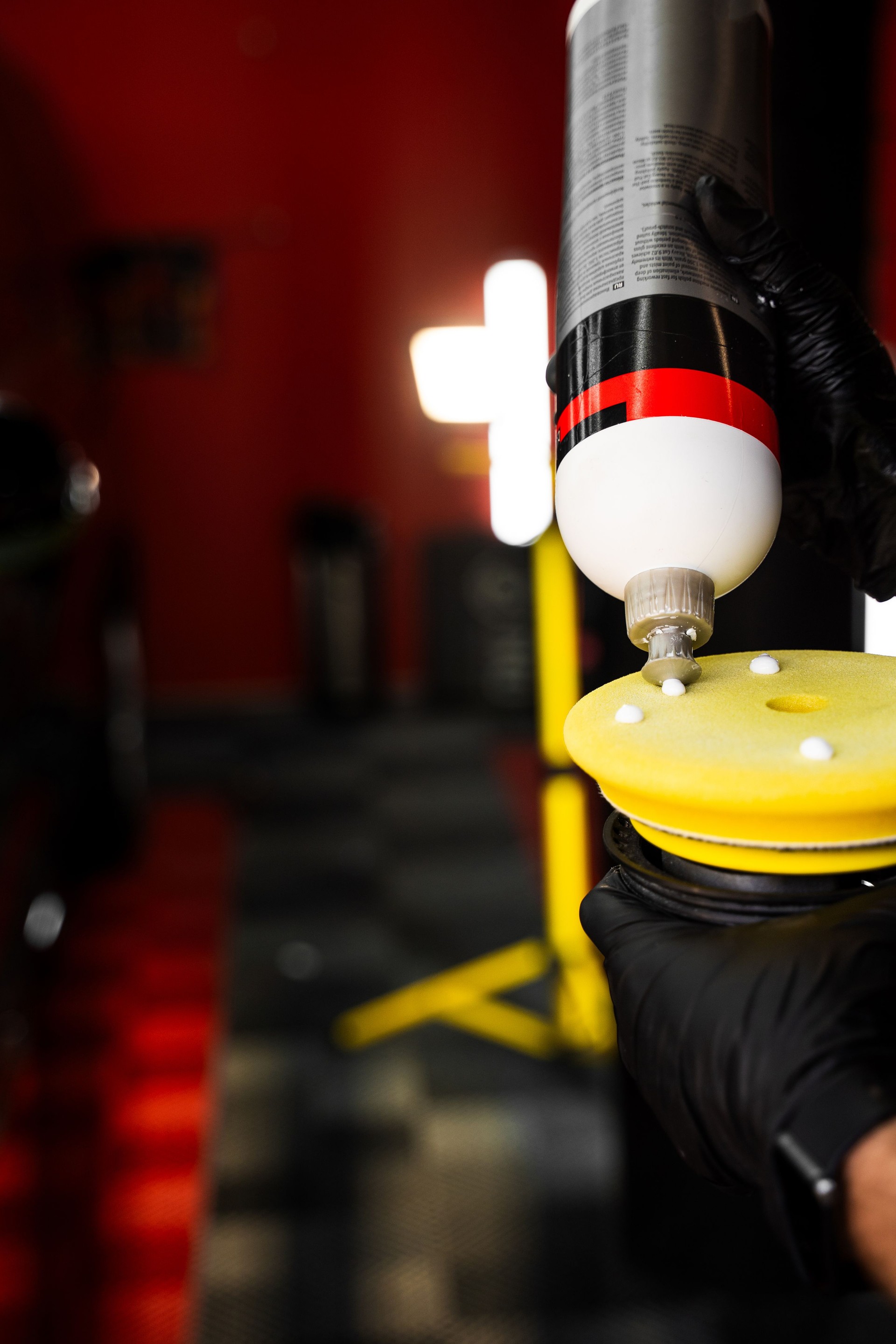 Applying compound to yellow polishing pad. Car detailing and paint correction preparation. Polishing compound is applied evenly to yellow foam pad, preparing surface for flawless paint correction.