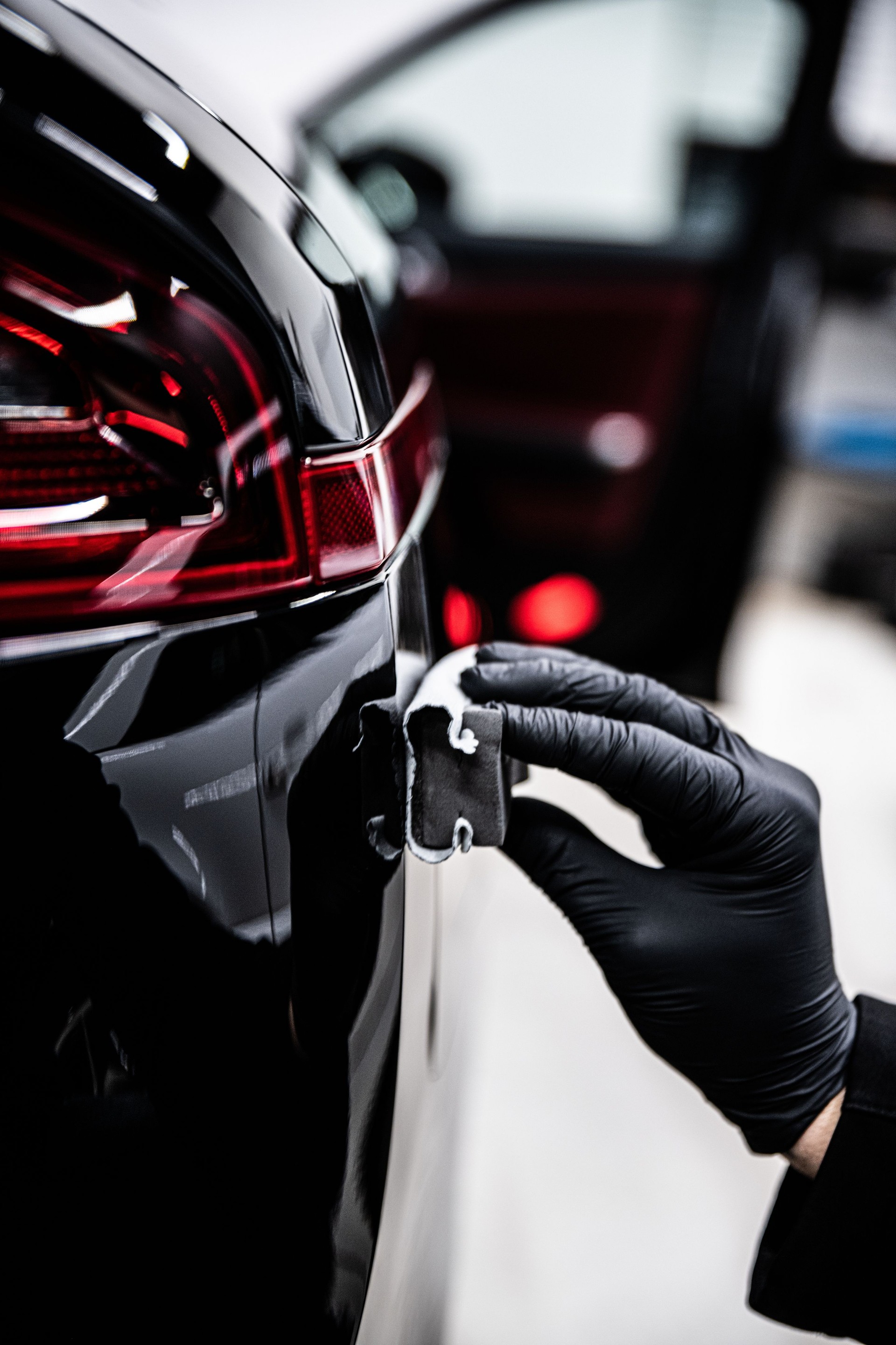 Mitarbeiter eines Detailing-Studios oder einer Autowaschanlage trägt eine Keramik- oder Graphenbeschichtung auf